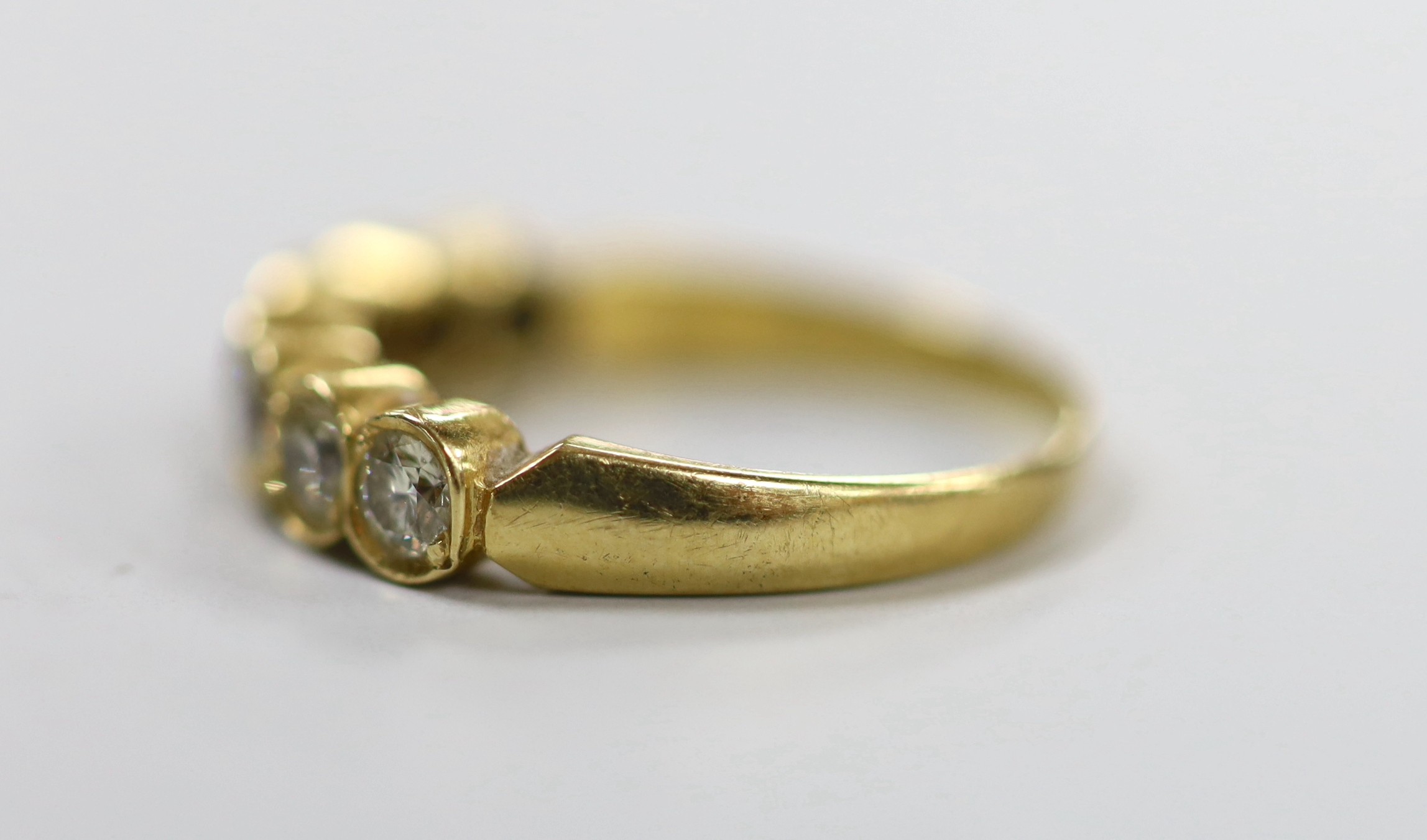 A modern 750 yellow metal and seven stone diamond set half hoop ring, size O, gross weight 3.2 grams.